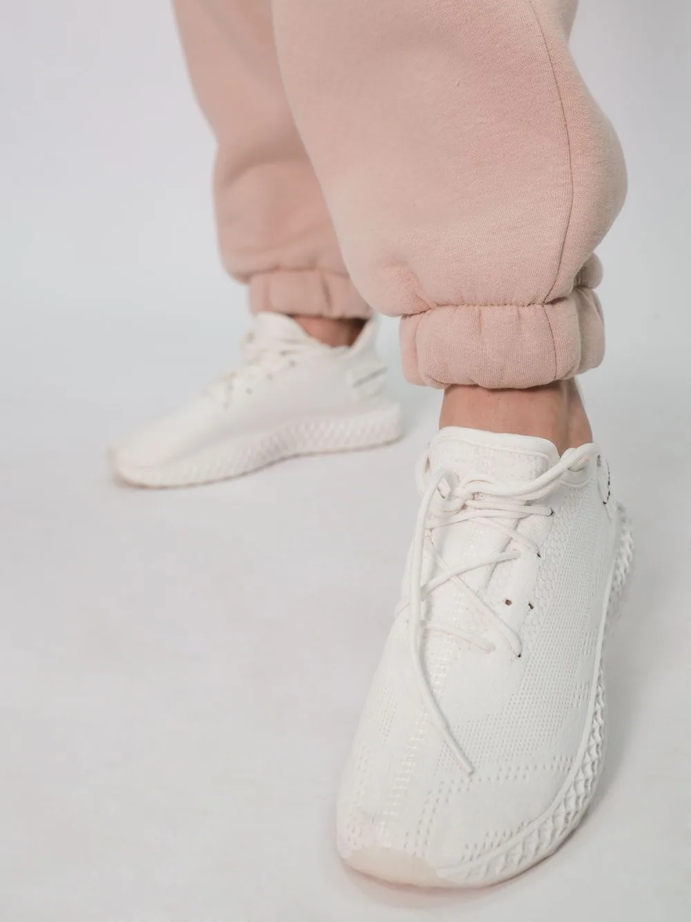 White lace-up sneakers with neutral casual clothing; representative sneaker image. Representative image, not a photograph of White Air Force 1's.