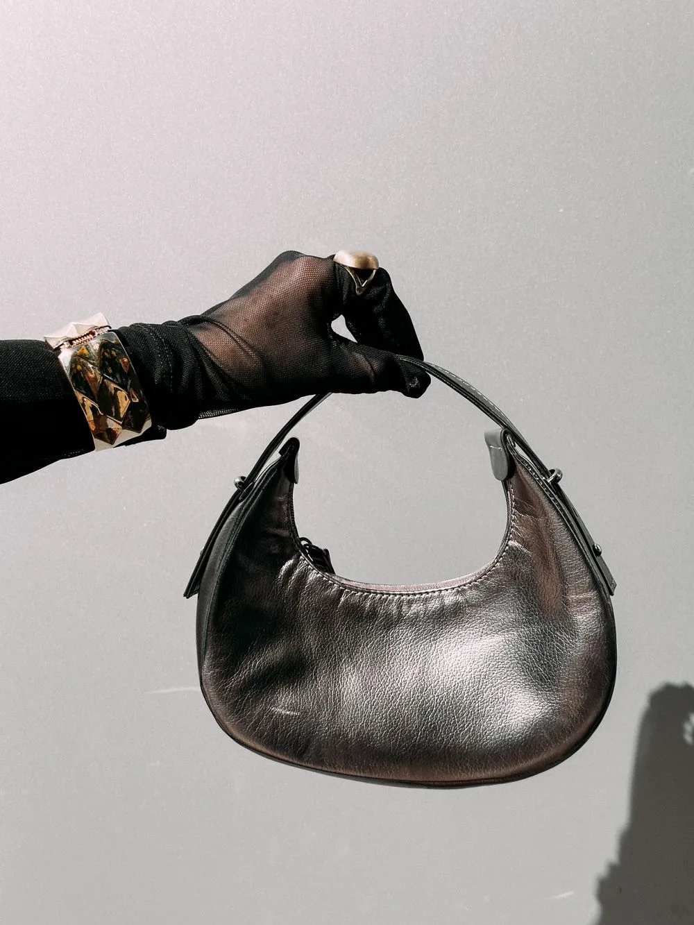 Metallic silver handbag held by a gloved hand; representative handbag image. Representative image, not a photograph of Sparkle Top Handle Bags.